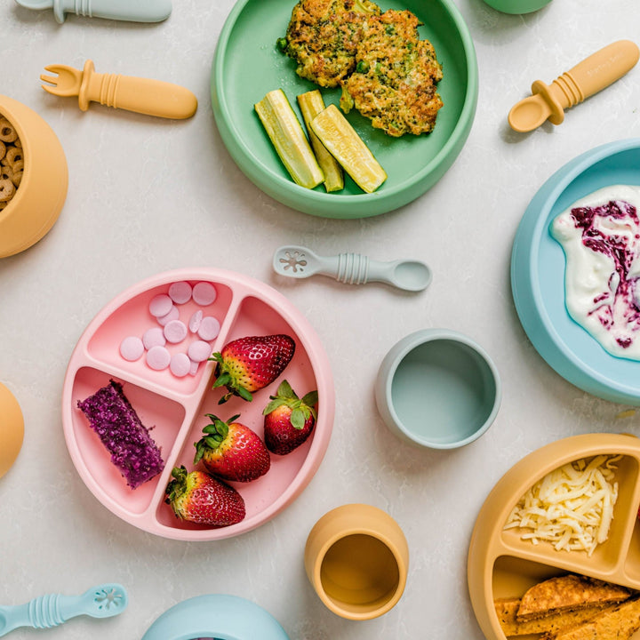 Feeding products, suction plates and bowls on a white marble background.