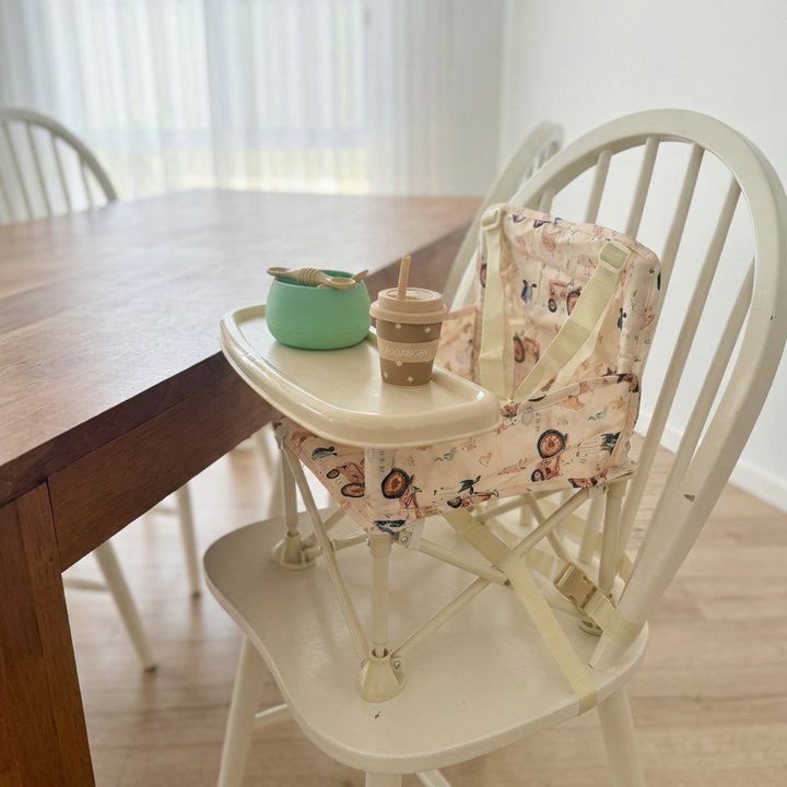 image shows the farm yard campie chair anchored to a dining chair to be used at the dinner table for a family meal.