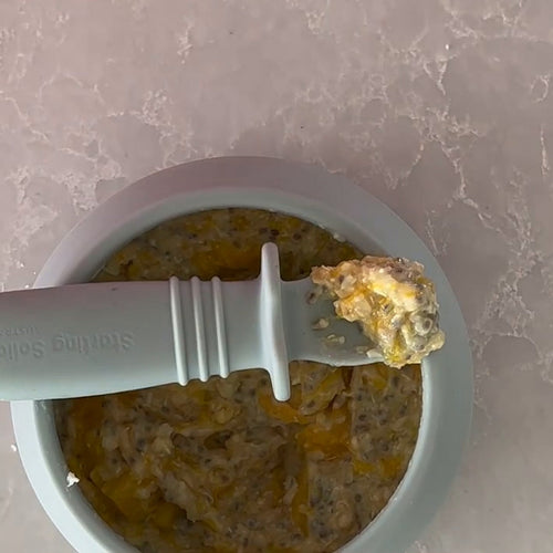 Mango and quinoa breakfast cereal for babies in a blue bowl with a Sticky Spoon