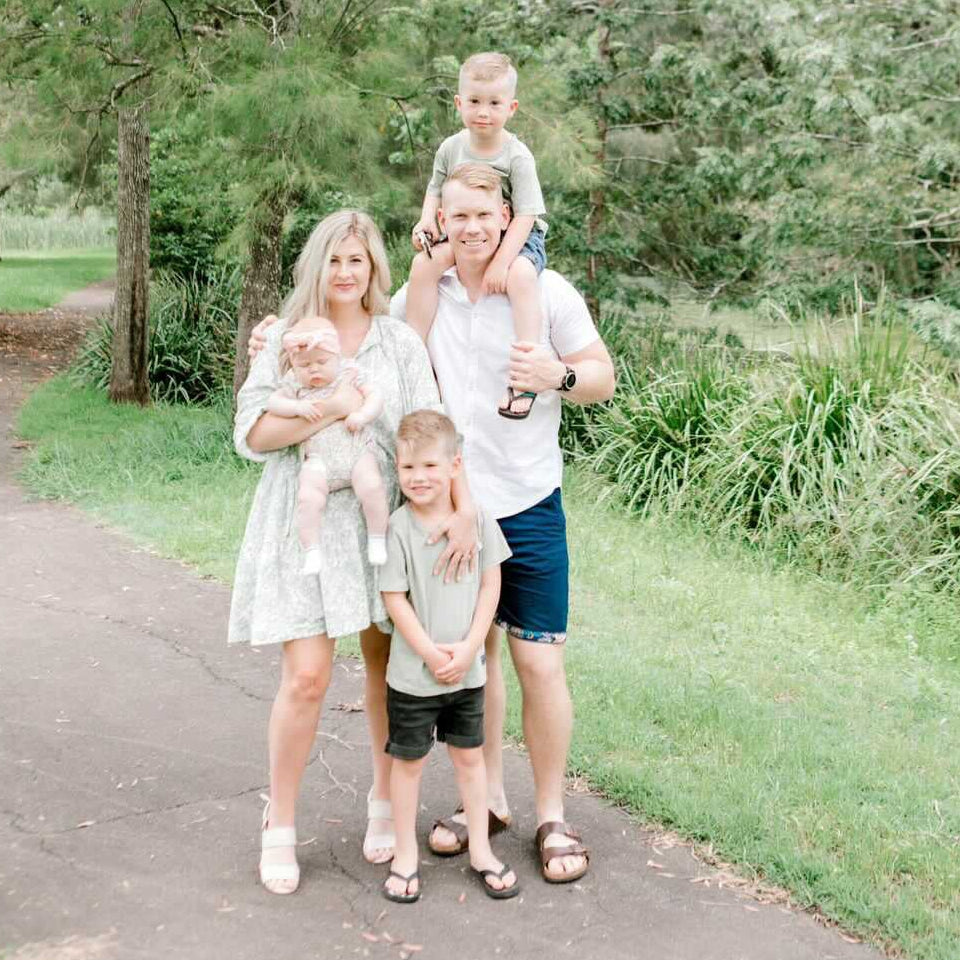 Family of four standing on a path in a park with trees in the background