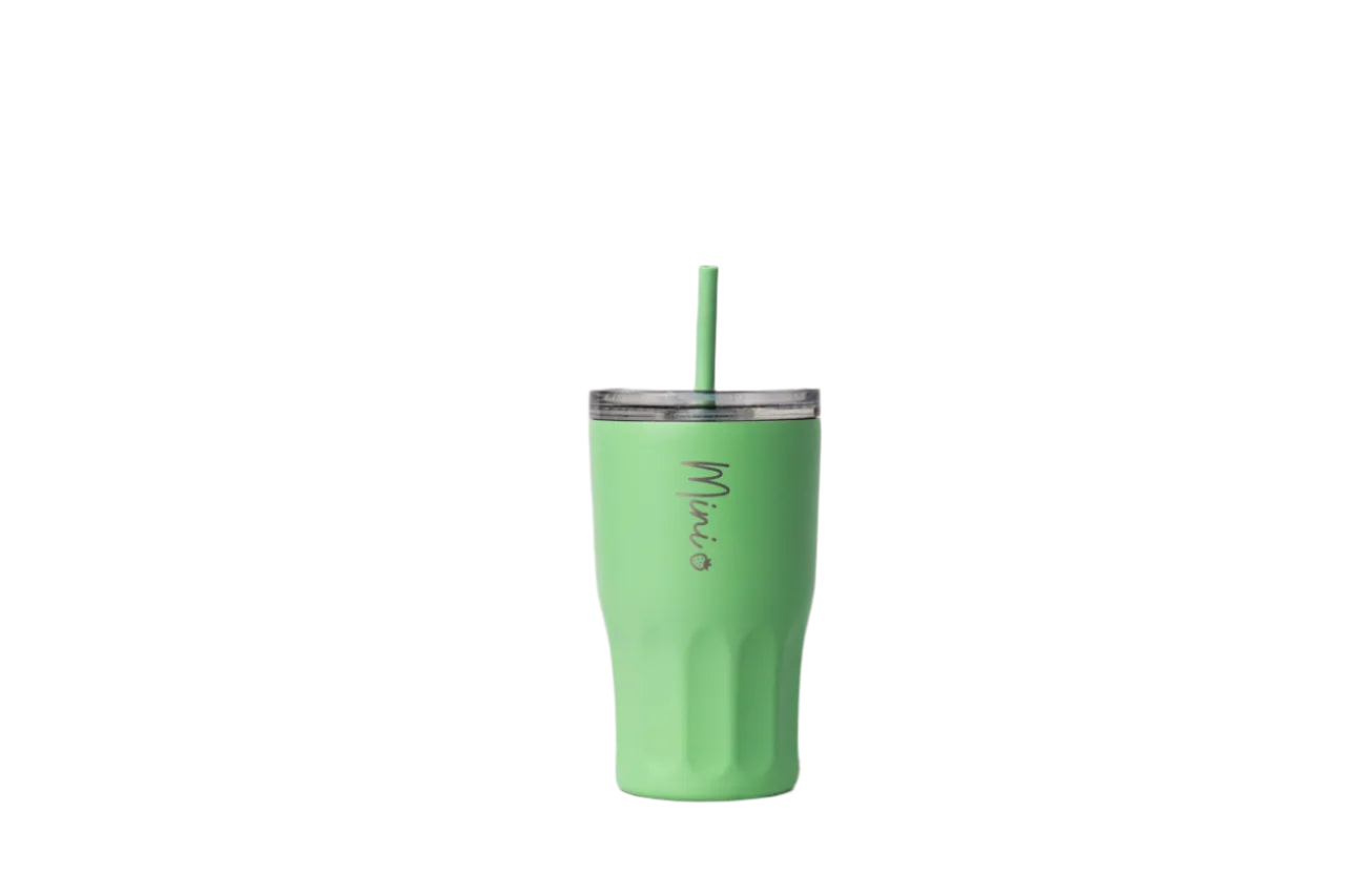 Green tumbler with a straw on a marble surface