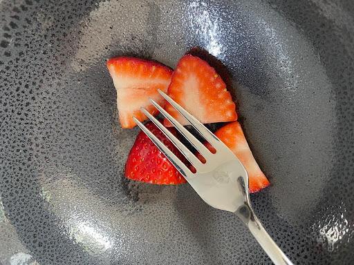Chopped strawberries in a grey bowl with a fork