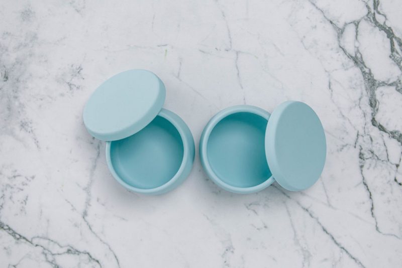 Birdseye view of Suckie Scoop Mini Bowls with lids in 'Blue Lemonade' on a marble bench.