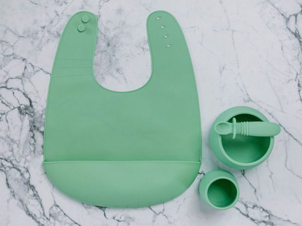 Green (Mint Crisp) silicone bib, cup, bowl and spoon set for babies on a marble bench by Starting Solids Australia