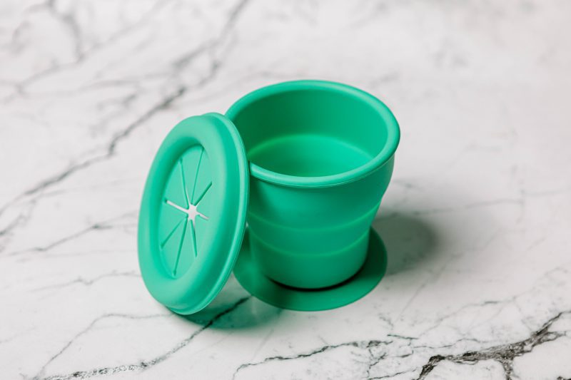 Green silicone Snackie Cup for babies by Starting Solids Australia on a marble bench.