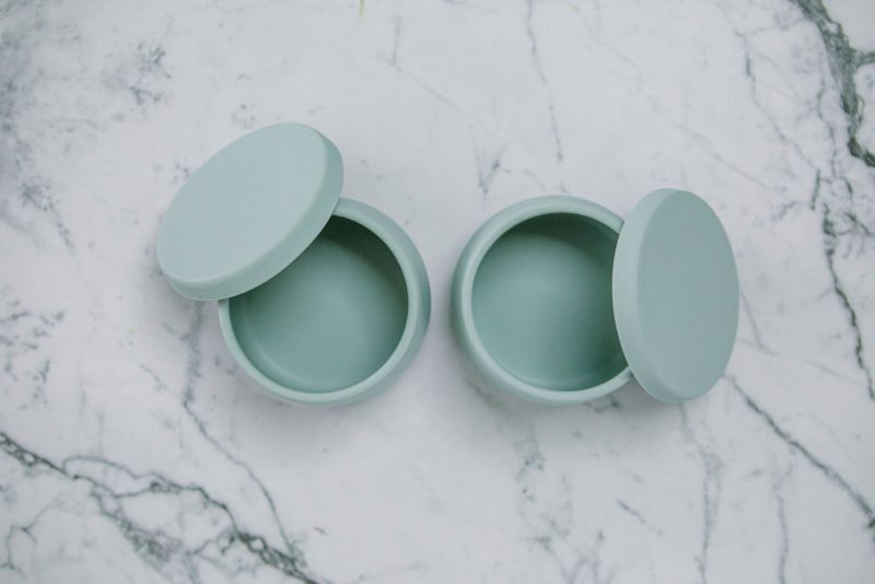 Birdseye view of Suckie Scoop Mini Bowls with lids in 'Meringue' on a marble bench.