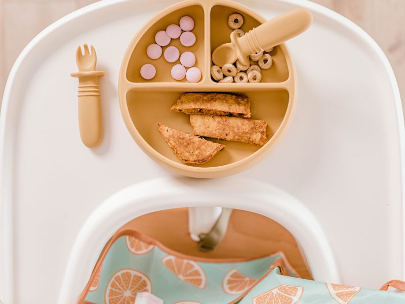 Birdseye view of silicone Suckie Scoop Divided Plate and Self Spoon Set in 'Biscoff' yellow by Starting Solids Australia on a Tripp Trapp highchair tray.