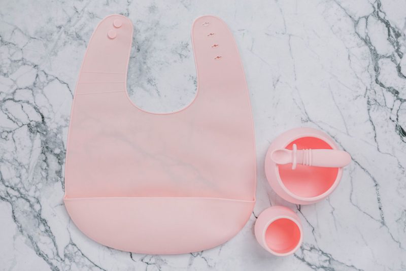 Pink (Fairy Floss) silicone bib, cup, bowl and spoon set for babies on a marble bench by Starting Solids Australia
