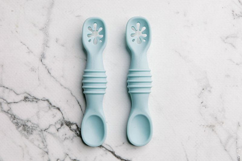 Blue silicone sticky spoons for baby on a marble bench by Starting Solids Australia