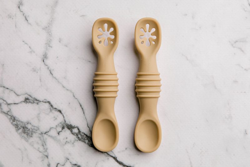 Yellow silicone sticky spoons for baby on a marble bench by Starting Solids Australia