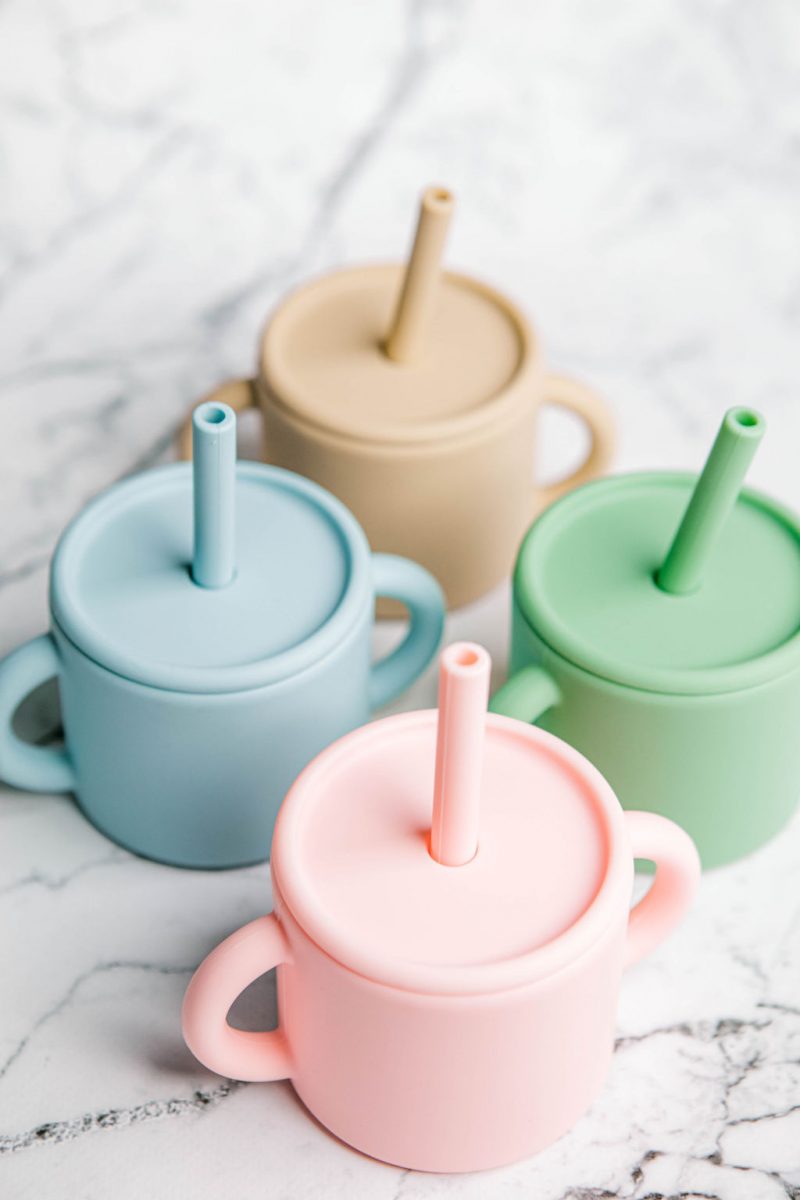 Four different coloured Ideal First Baby Cups by Starting Solids Australia on a marble bench