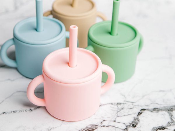 Four different coloured Ideal First Baby Cups by Starting Solids Australia on a marble bench