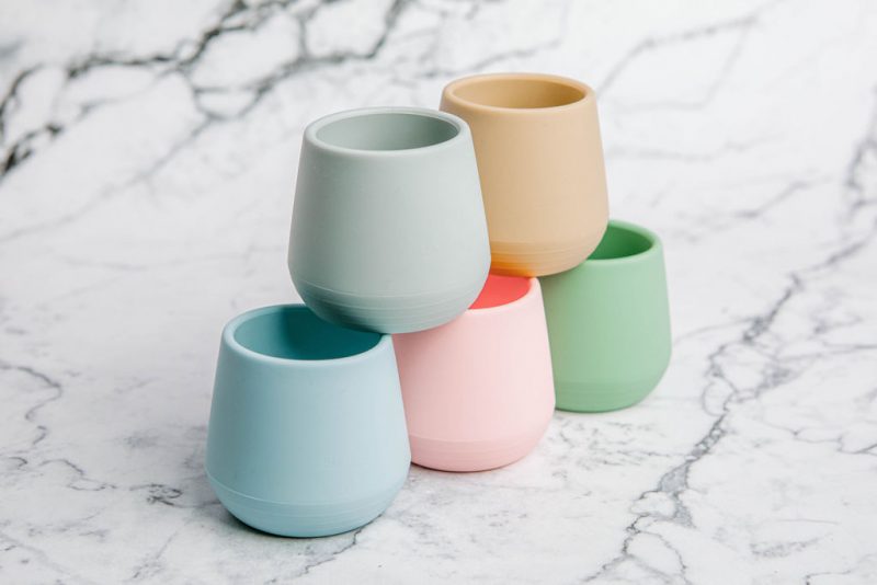 Stack of five Bubbie Cups in assorted colours by Starting Solids Australia, on a marble bench.
