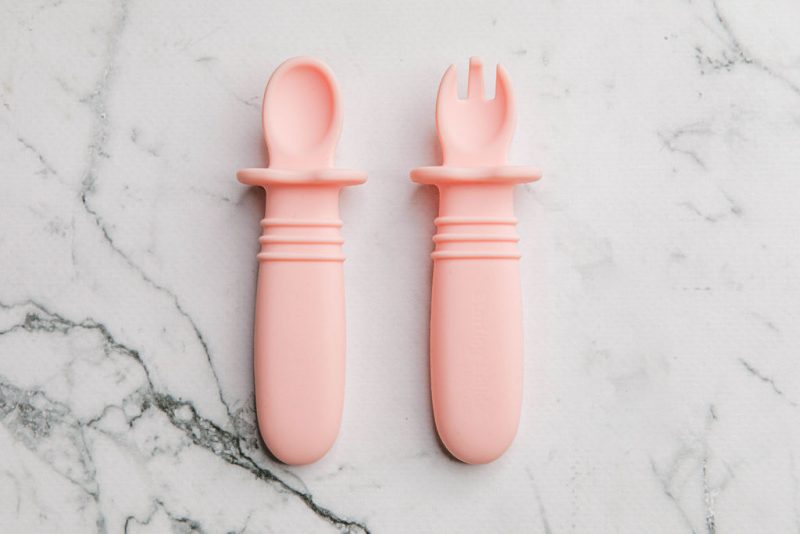 Pink silicone baby cutlery on a marble bench by Starting Solids Australia