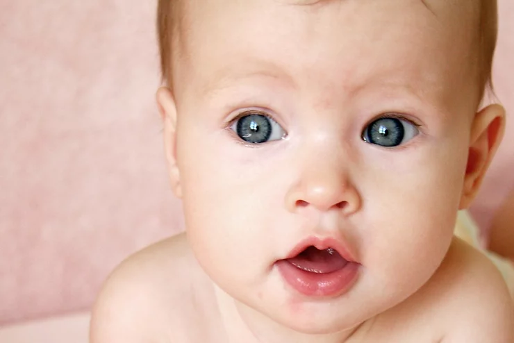 Blue eyed baby (face detail) with a pink background