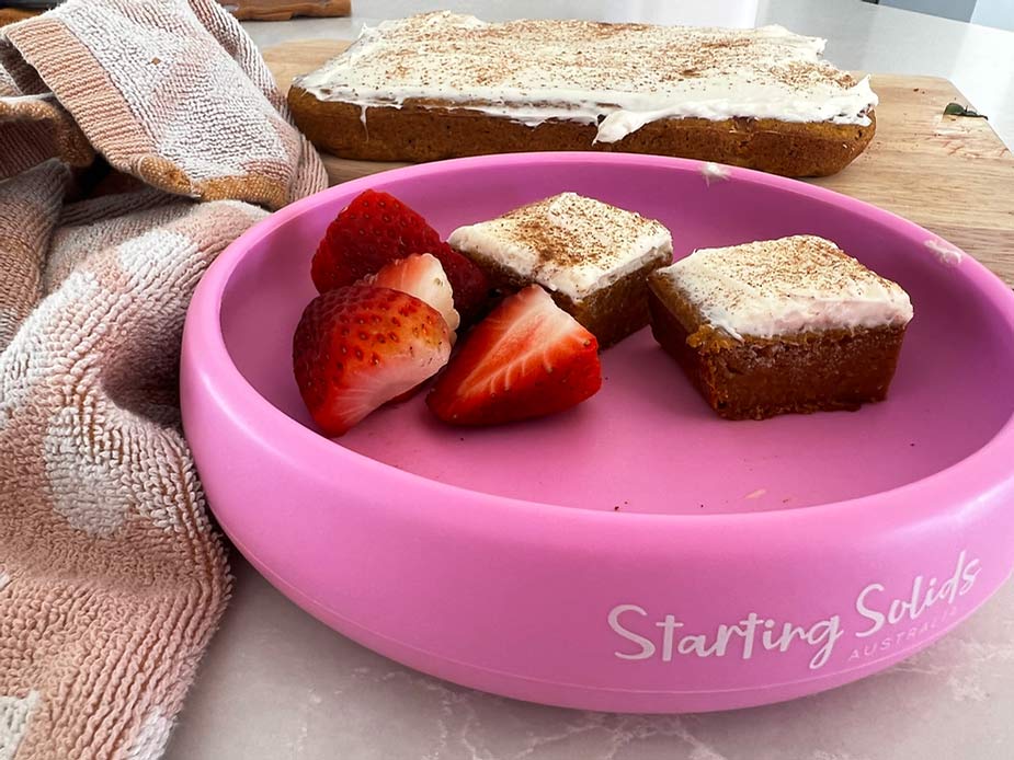 Pumpkin Spice Bread and sliced strawberries in a pink Suckie Scoop Plate on a bench by Starting Solids Australia.
