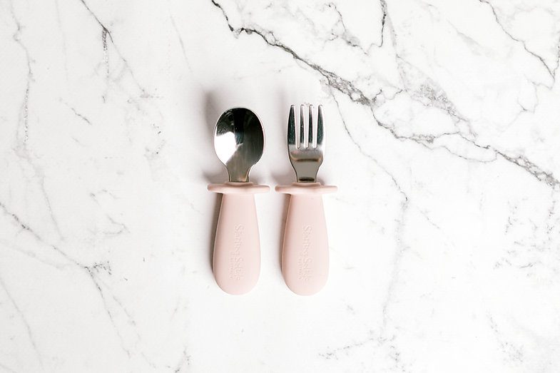 Pastel Pink Toddler Silvies (spoon and fork) by Starting Solids Australia on a marble bench.