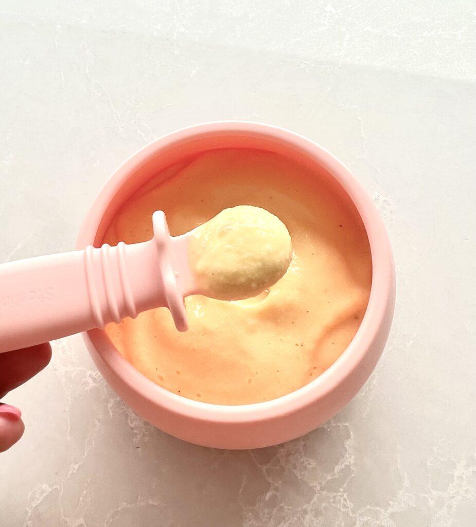 Mango sorbet puree in pink silicone bowl with spoon by Starting Solids Australia