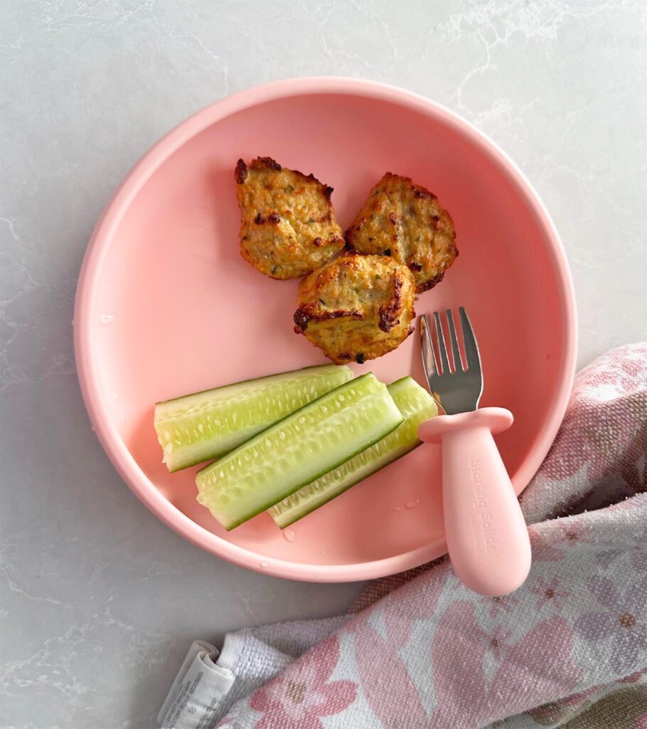Chicken Bites (nuggets) with fresh cucumber by Starting Solids Australia on a pink Suckie Scoop Plate.